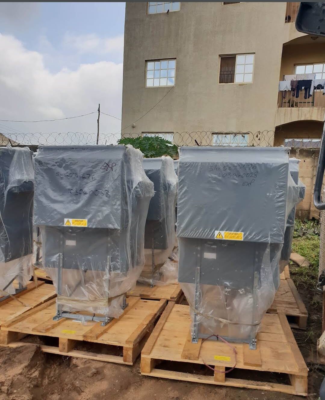 Wrapped electrical equipment units on wooden pallets awaiting delivery