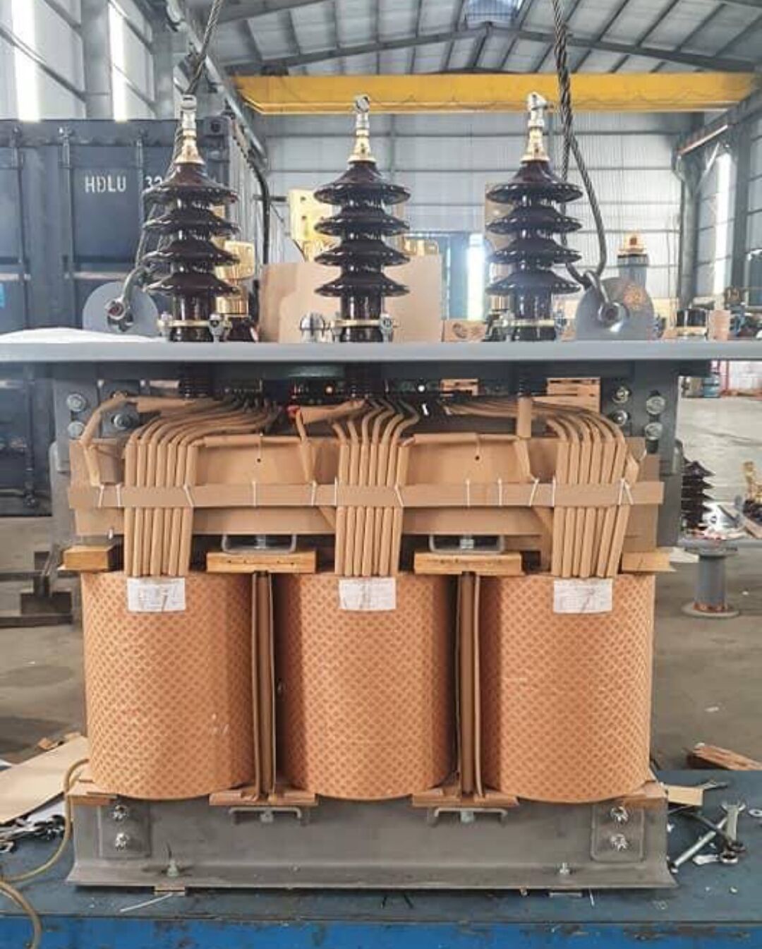 Transformer core and windings with porcelain bushings mounted above